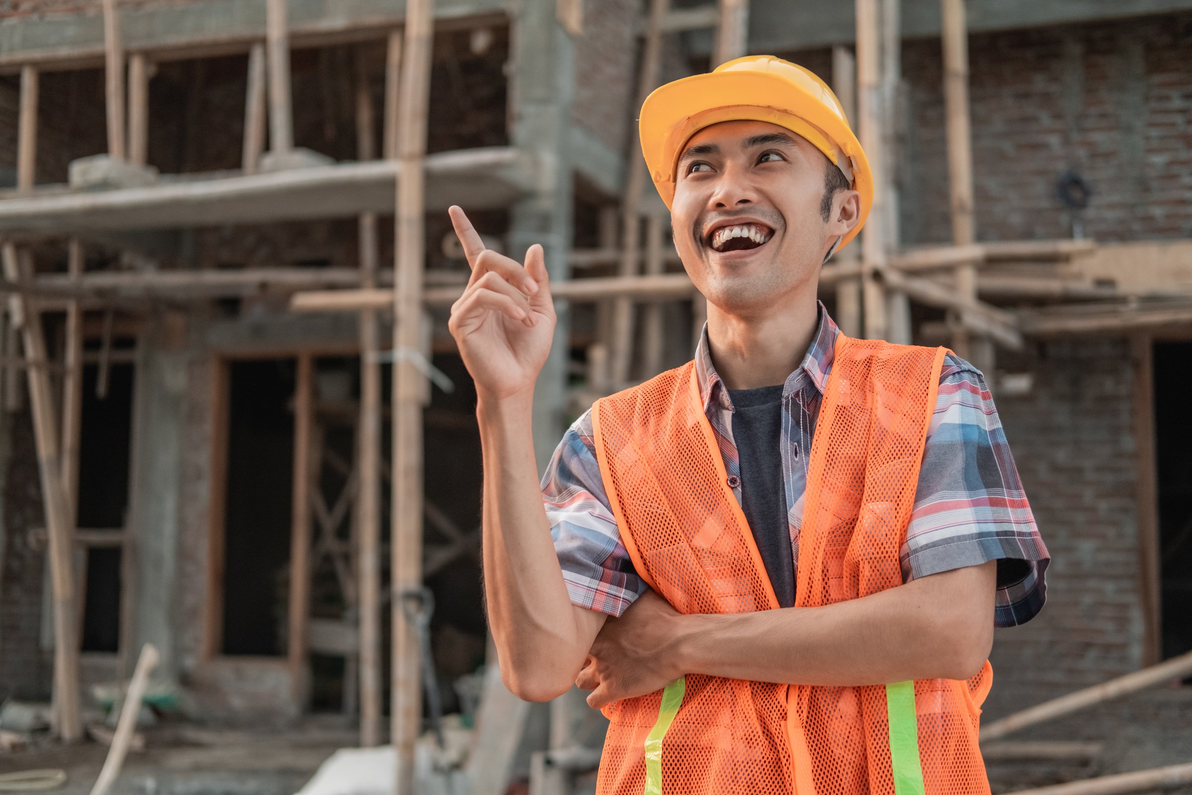 An Asian Contractor Stands Wearing a Safety Helmet and Vest with a Gesture of Getting an Idea